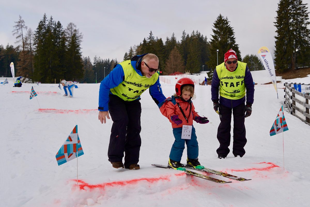 Integratives Wintersportfestival: Betreuer begleiten ein Kind auf Skiern