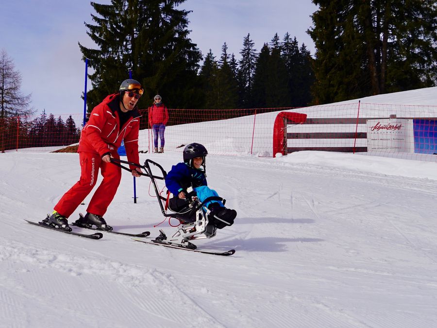 Sitzski mit Begleitperson auf der Piste